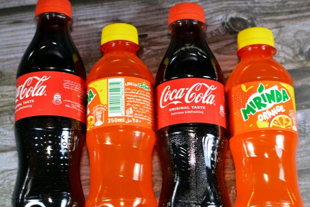 Individual bottled sodas on a wooden table.