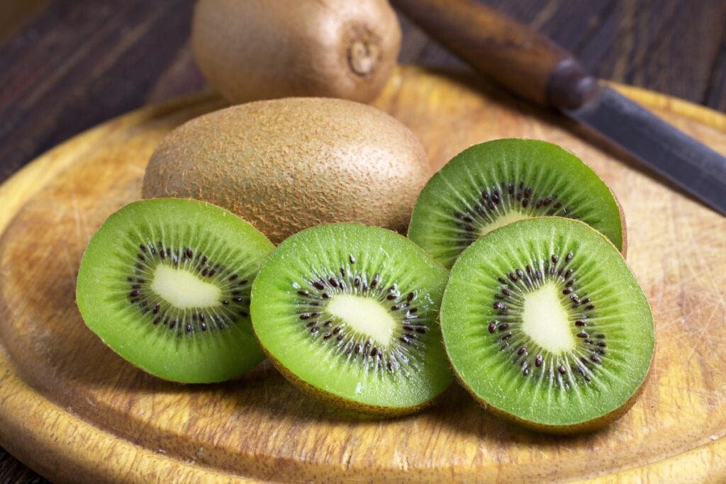Sliced kiwis on a wooden board.