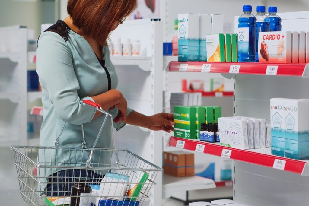Woman selecting over-the-counter medicine from a shelf in a drugstore.
