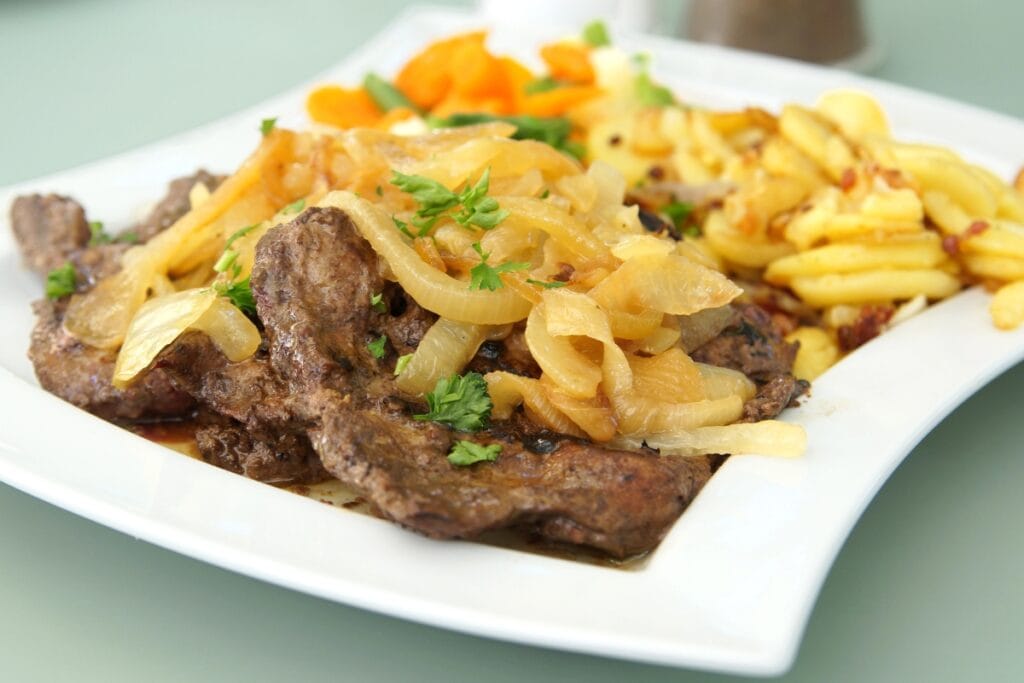 Liver and onions on a square white plate.