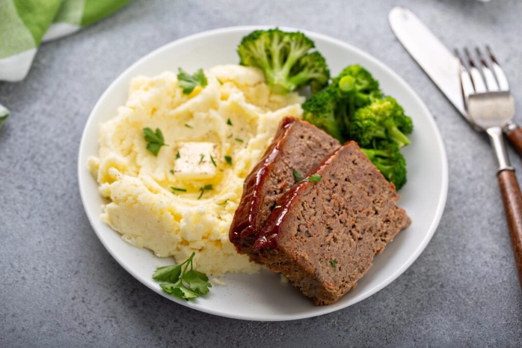 Meatloaf and mashed potatoes on a white plate.