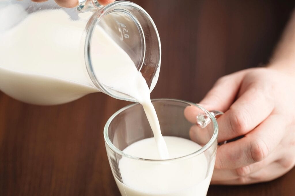 Pouring milk into a cup.