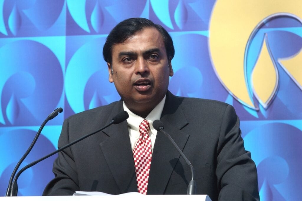 Mukesh Ambani speaking on stage with a microphone.