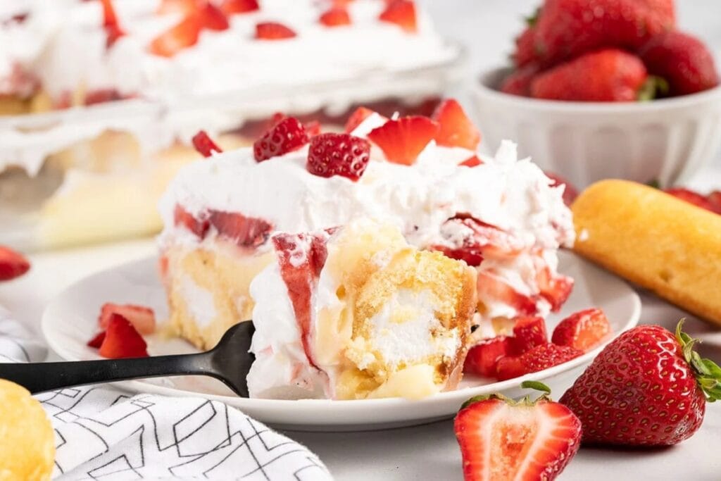 Slice of No-Bake Twinkie Cake with strawberries and whipped topping on a plate.