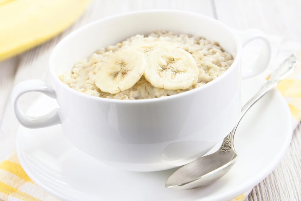 Oatmeal in a handled bowl topped with banana slices.