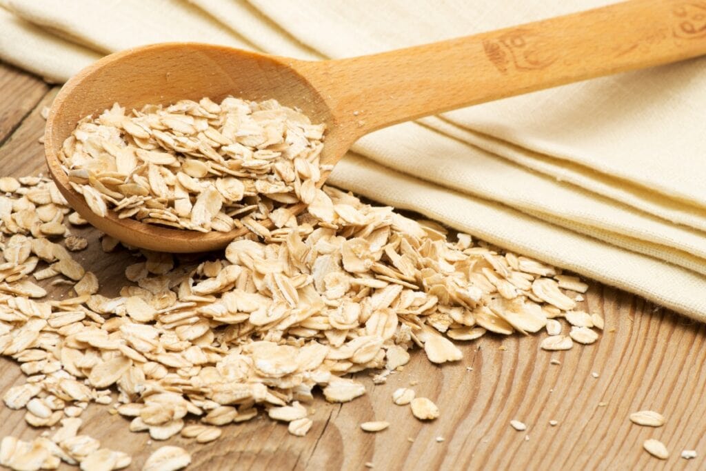Wooden spoon filled with dry oatmeal grains.