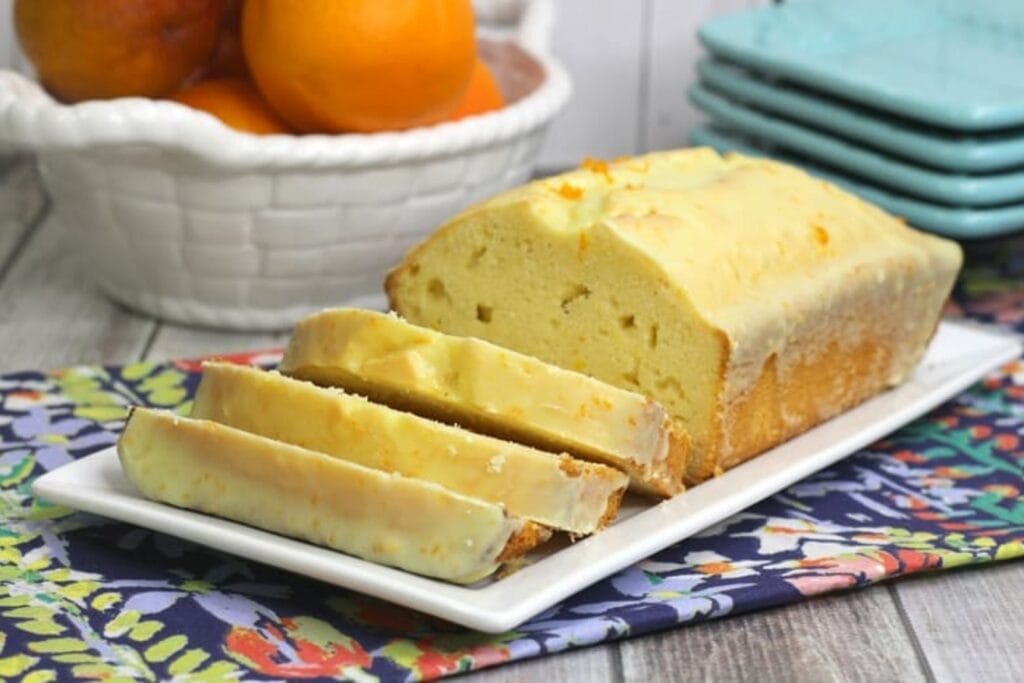Orange loaf cake on a rectangular white plate.