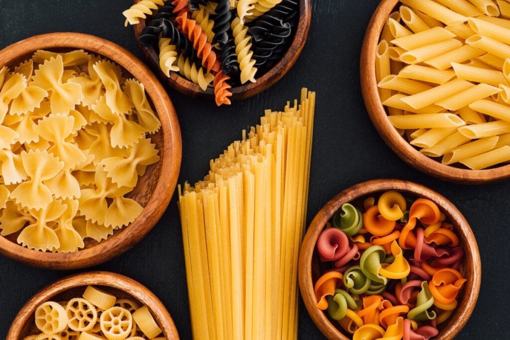 Different kinds of pasta in wooden bowls.