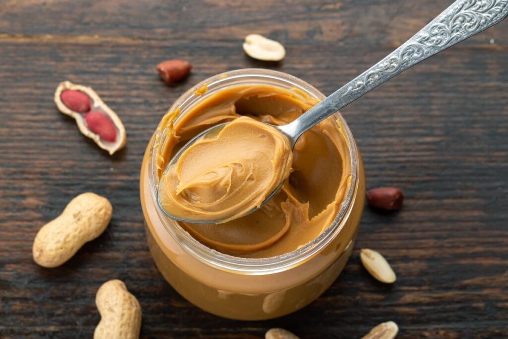 Jar of peanut butter with a spoonful scooped out.