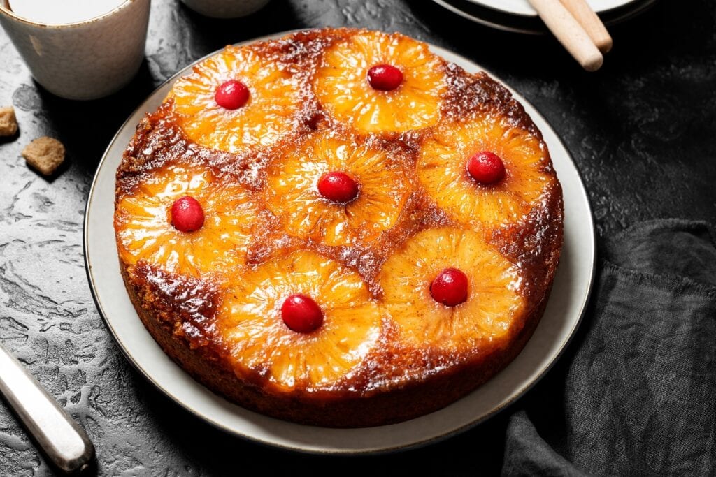 Pineapple upside-down cake on a white round plate.