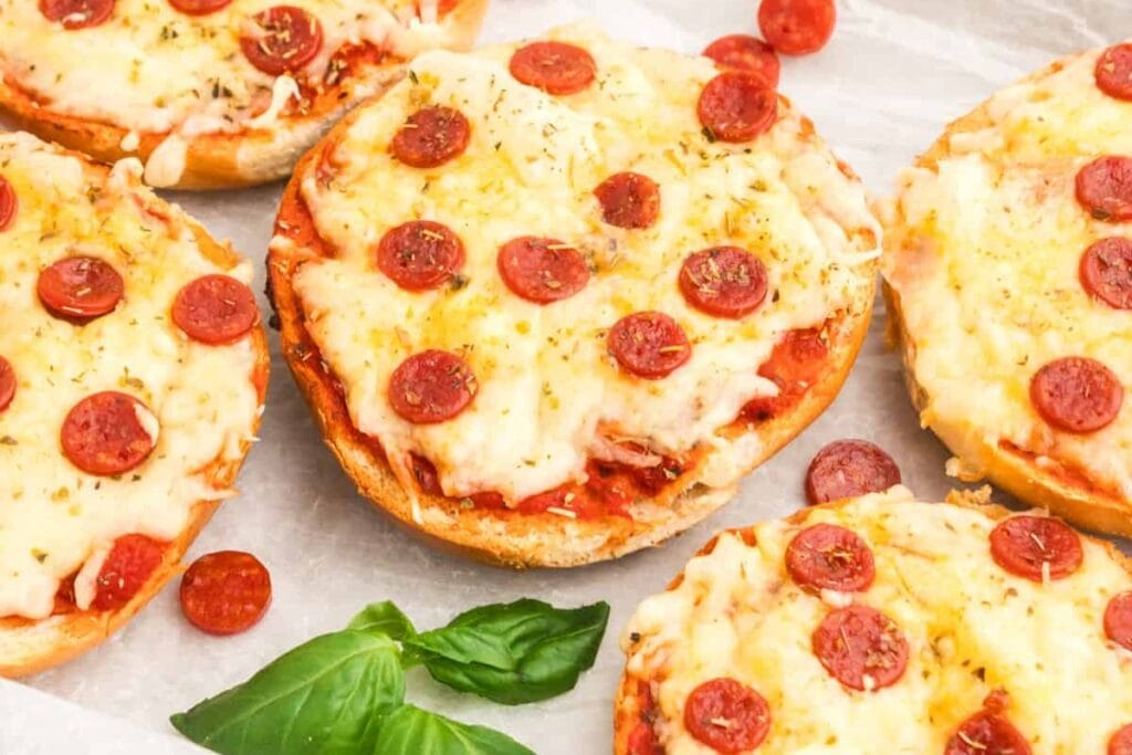 Pizza bagels placed on parchment paper.