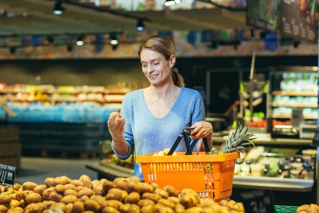 Woman holding a potato while shopping in the vegetable section.