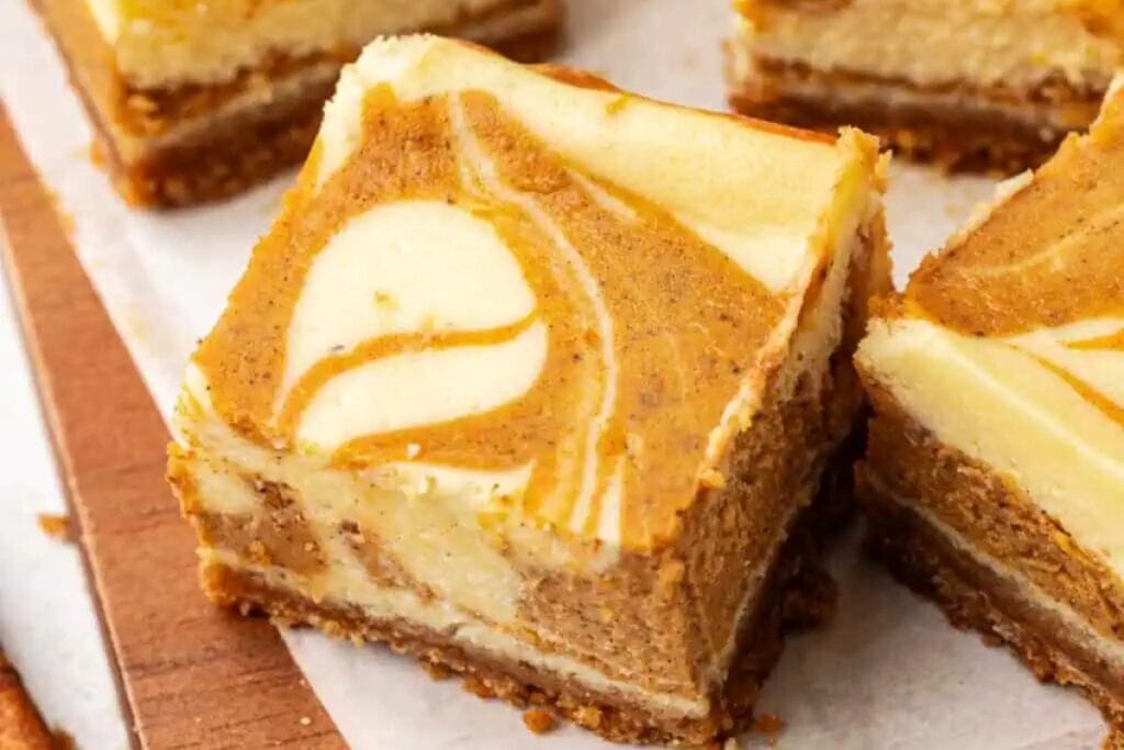Pumpkin cheesecake bars on a wooden board.