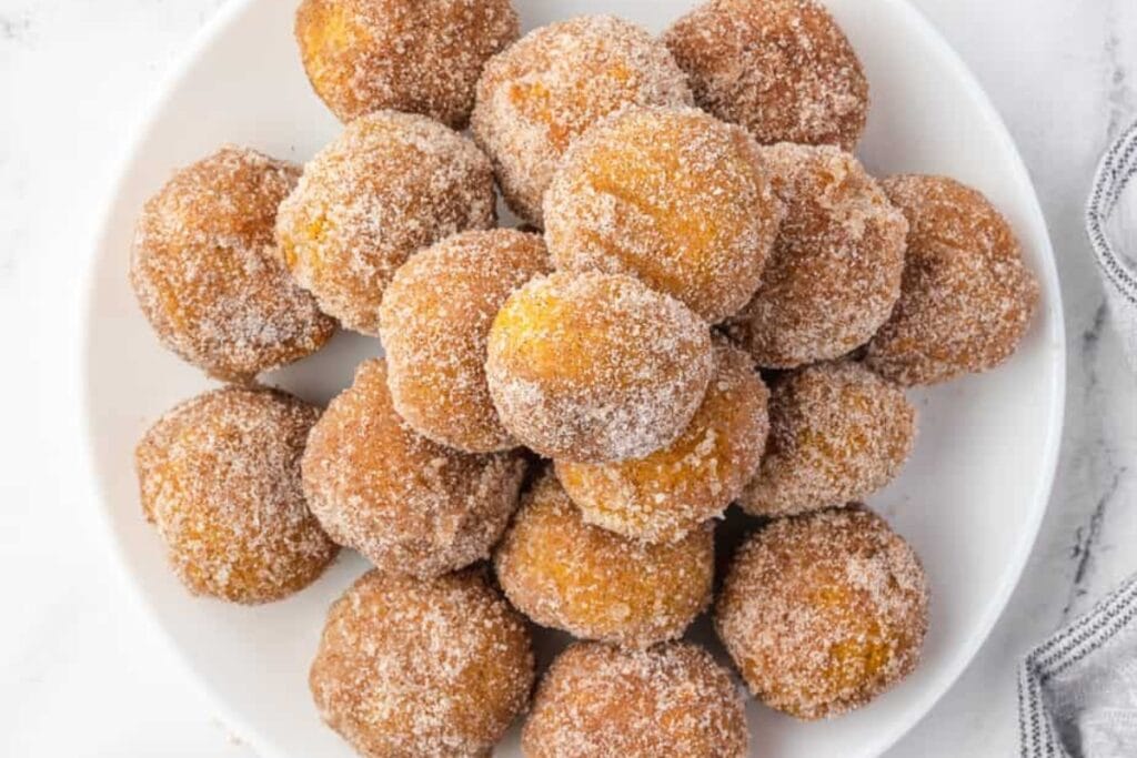 Pumpkin donut holes on a white plate.