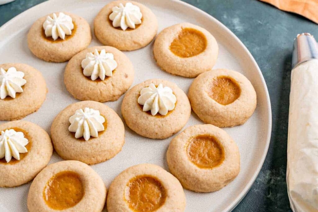 Pumpkin pie filled thumbprint cookies on a plate.