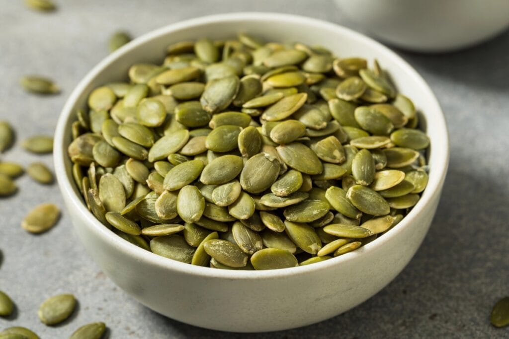 Pumpkin seeds in a white bowl.
