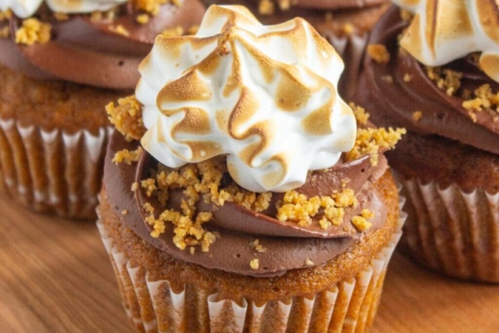 Pumpkin s'mores cupcakes on a wooden board.