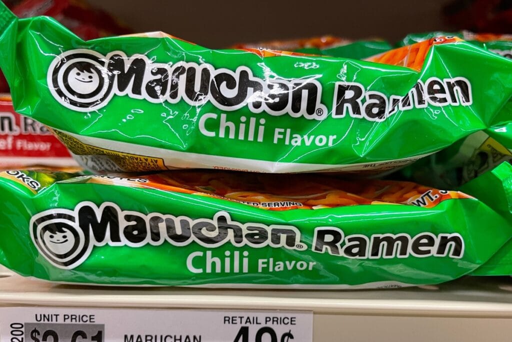 Two packs of ramen displayed on a shelf in a grocery store.