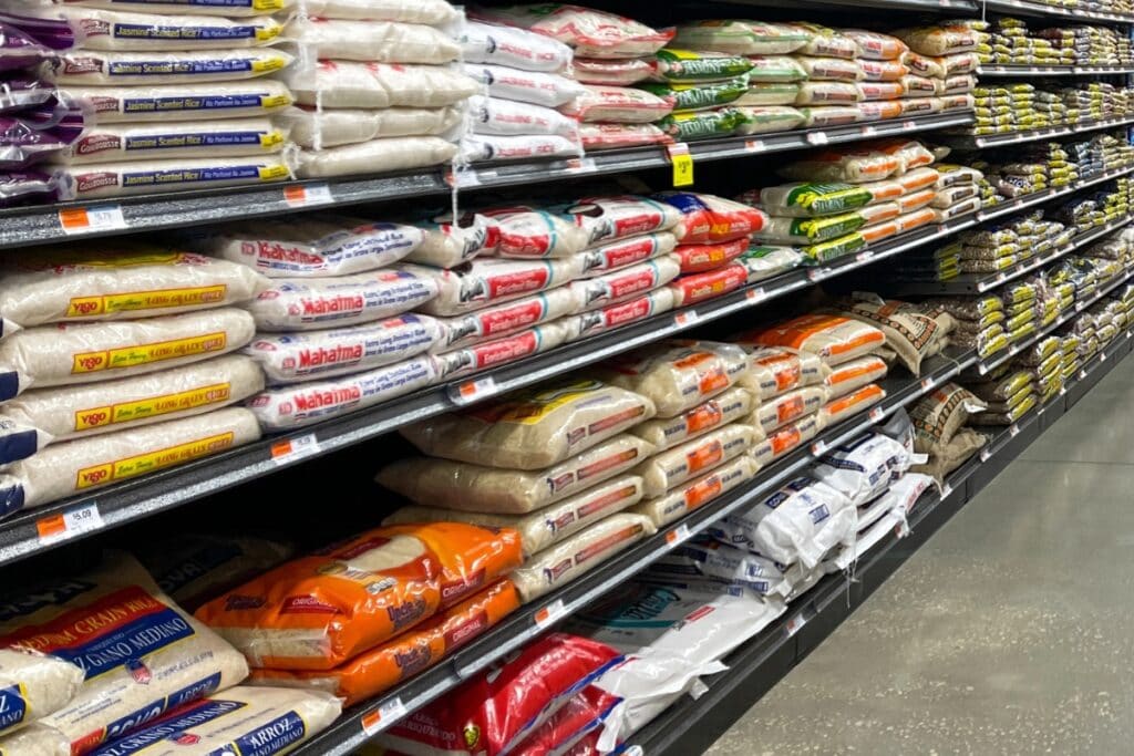 Multiple sacks of rice on a shelf in a grocery store.