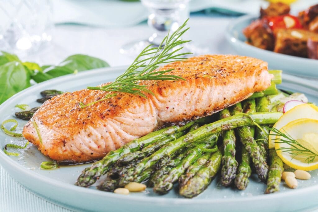 Salmon with asparagus on a white plate.