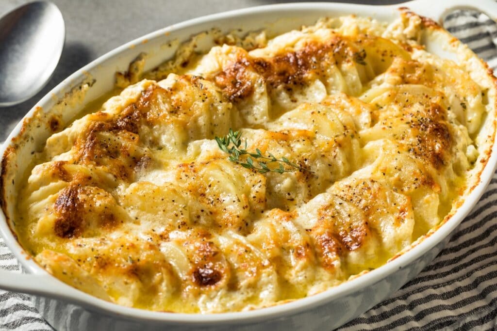 Scalloped potatoes in a white oval baking dish.