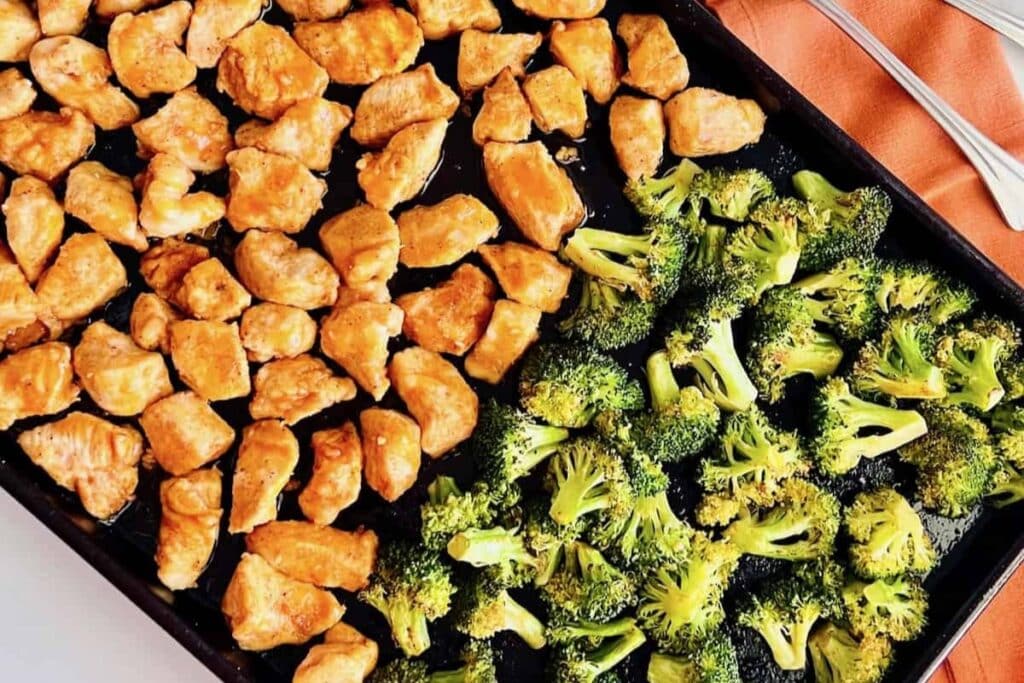 Buffalo chicken broccoli on a black sheet pan.