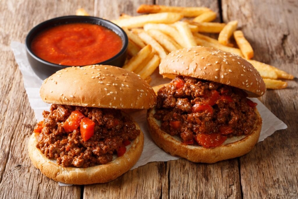Sloppy joes with fries and ketchup on a wooden table.