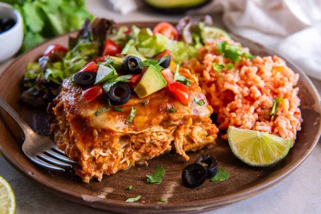 Slow cooker chicken enchiladas served on a plate with a fork.