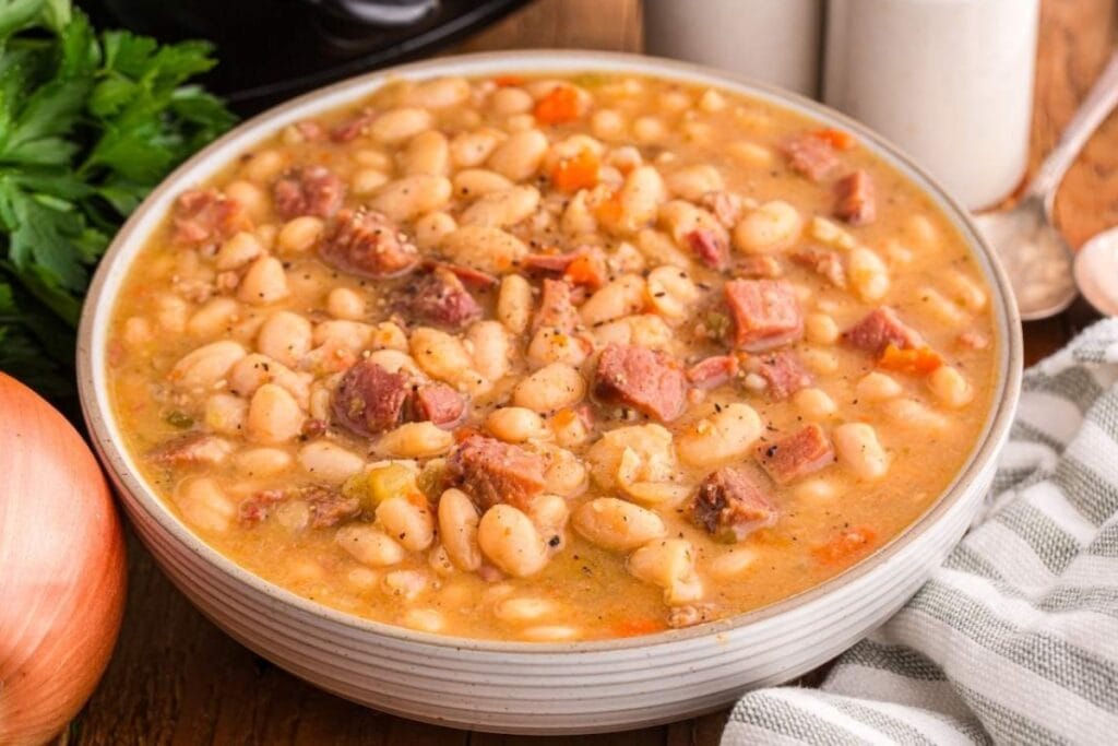 Slow cooker ham and bean soup in a white bowl.