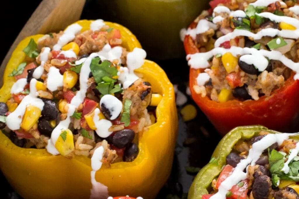 Slow cooker stuffed peppers filled with seasoned meat and rice, drizzled with sauce.