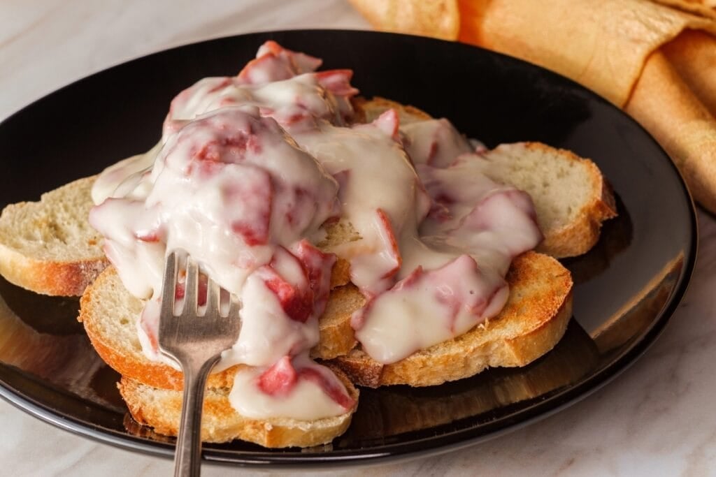Chipped beef and toast on a black plate.