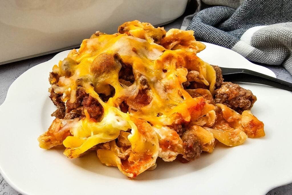 Sour cream beef casserole on a white plate with cutlery on the side.