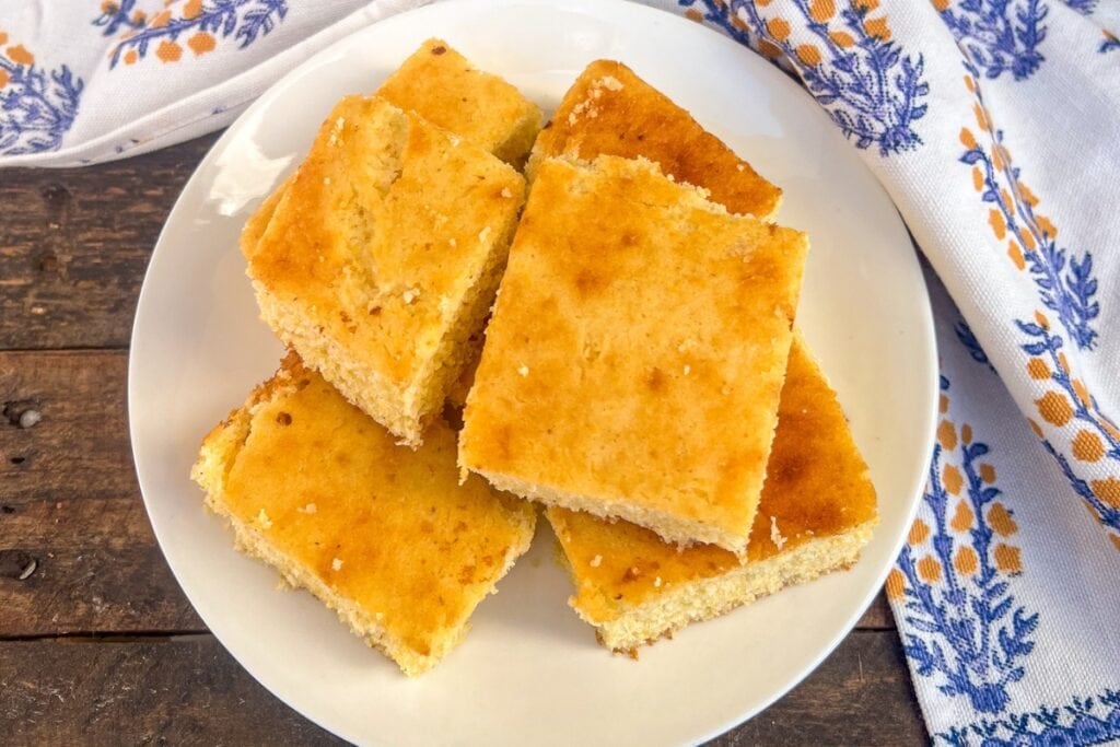 Slices of Southern skillet cornbread on a round white plate.