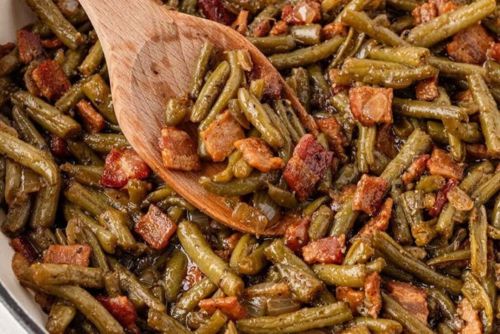 Southern smothered green beans scooped with a wooden spoon.