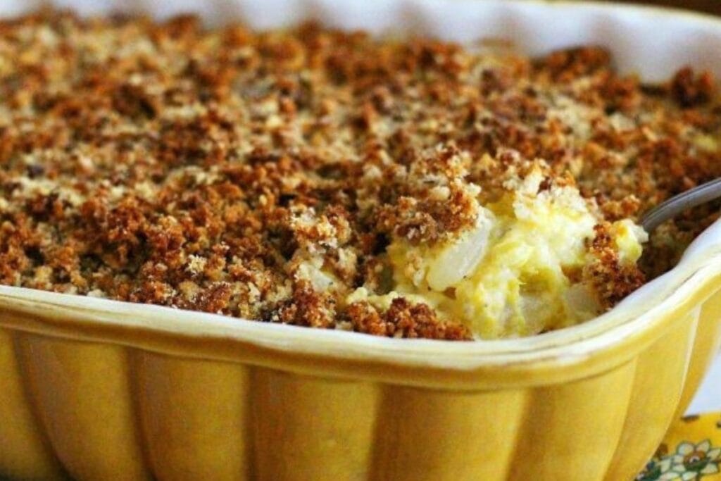 Southern squash casserole scooped with a spoon in a baking dish.