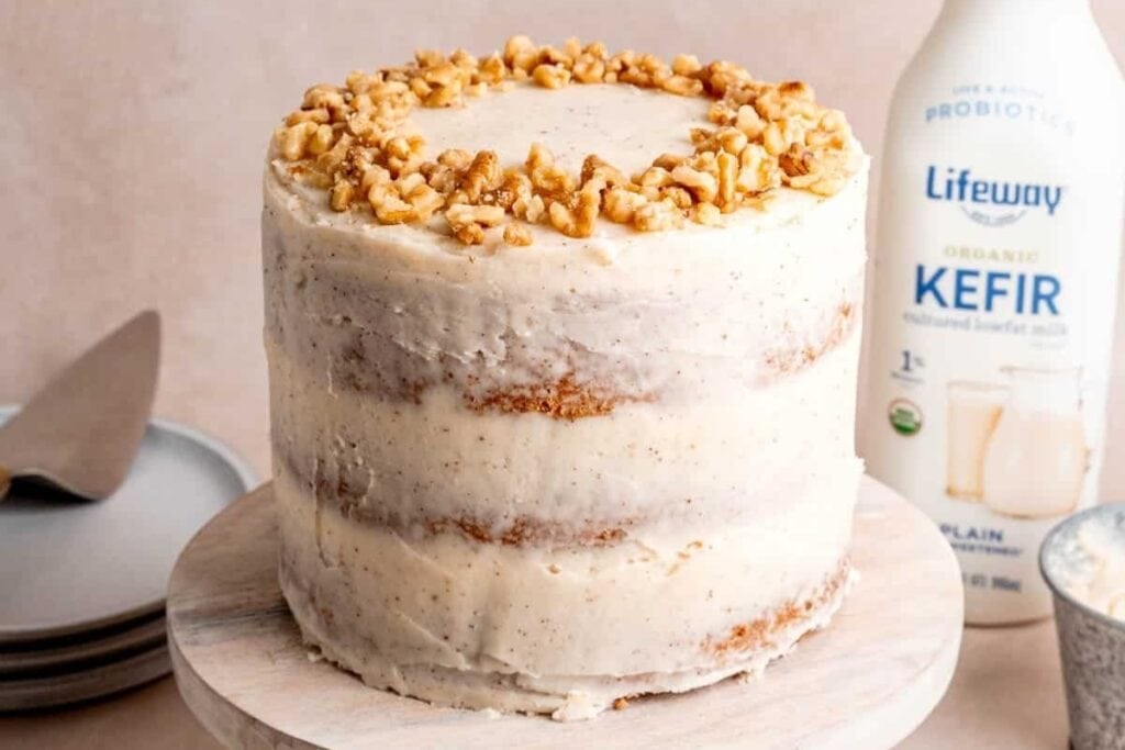 Whole spiced walnut cake on a round marble stand.