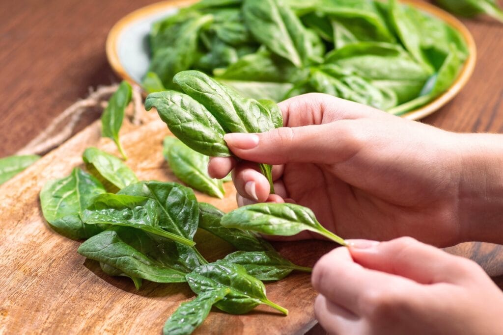 Spinach on hand, plate, and wooden board.