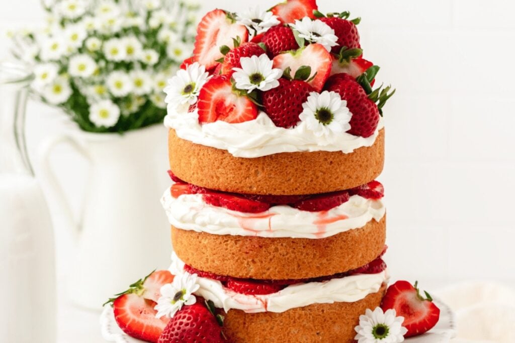 Strawberry shortcake layer cake with frosting and strawberries.