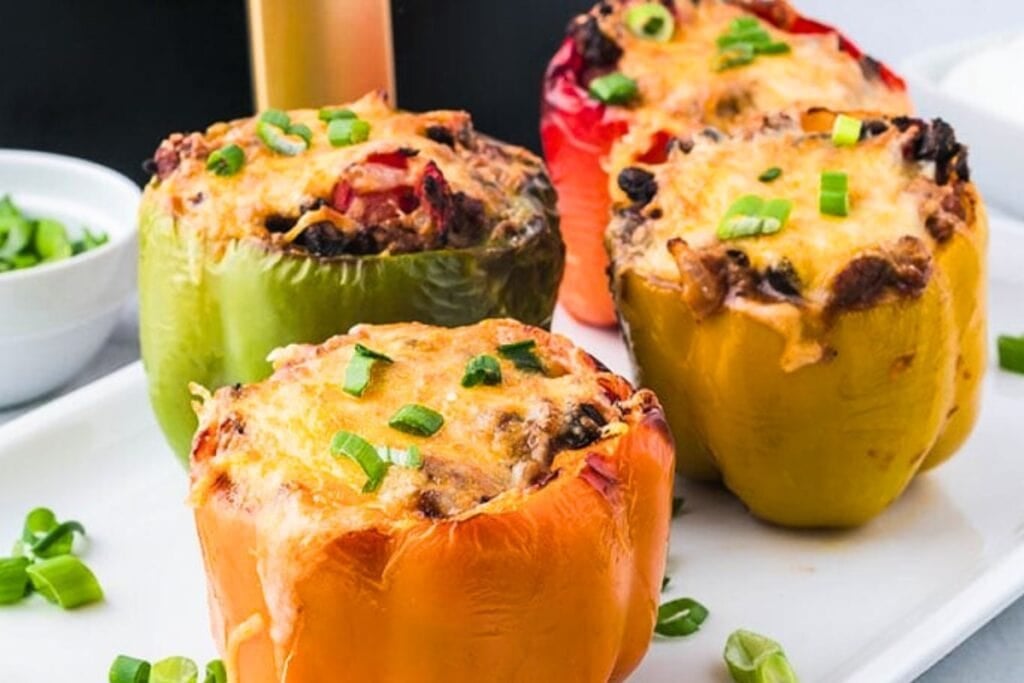 Stuffed peppers served on a white rectangular plate.