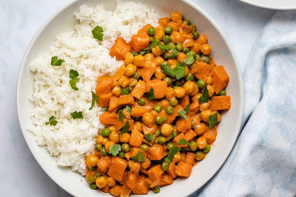 Sweet potato chickpea coconut curry served with rice on a plate.