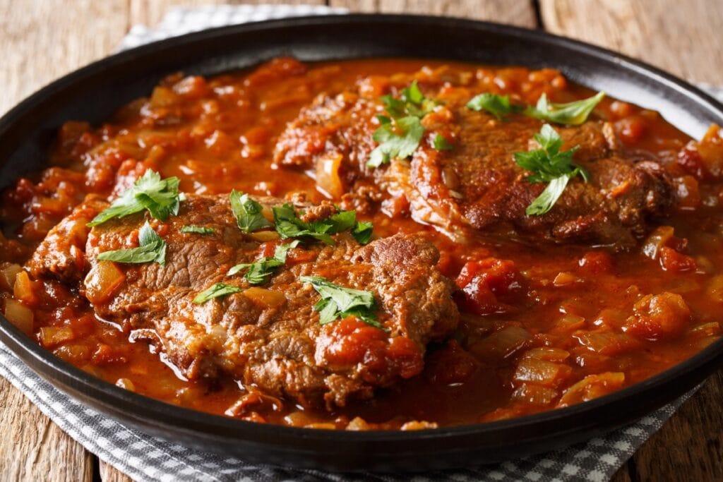 Swiss steak in a black shallow bowl.