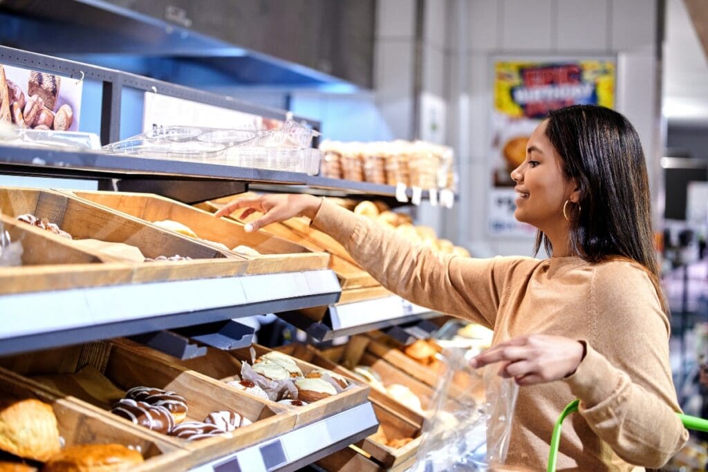Woman shopping at the bakery section in a grocery store during evening markdowns.