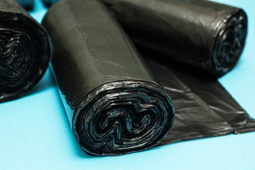 Black trash bags on a sky blue surface.