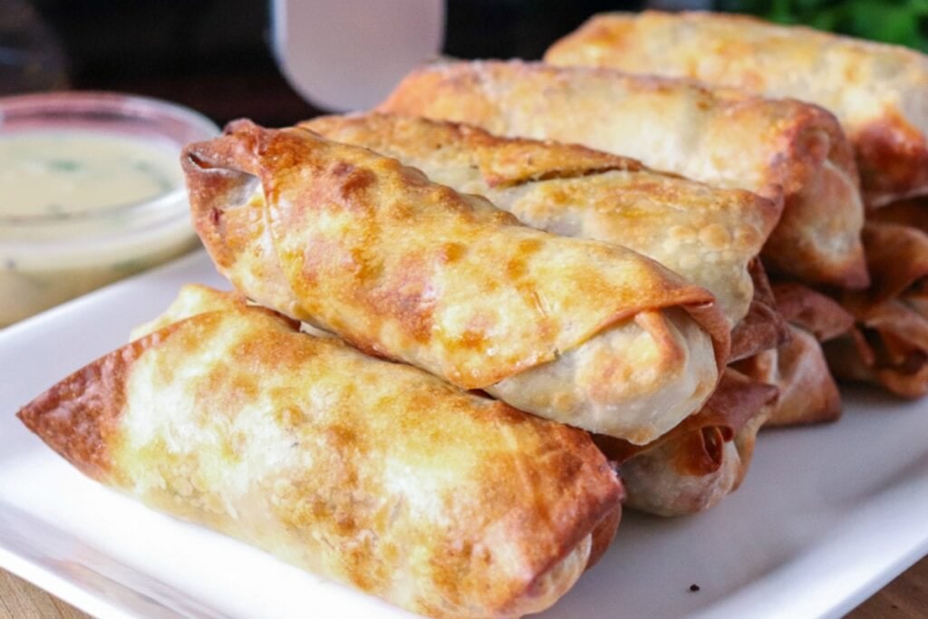 Crispy turkey stuffing egg rolls on a white rectangular platter.