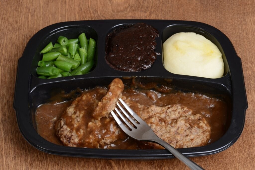 TV dinners on a wooden table with a fork.