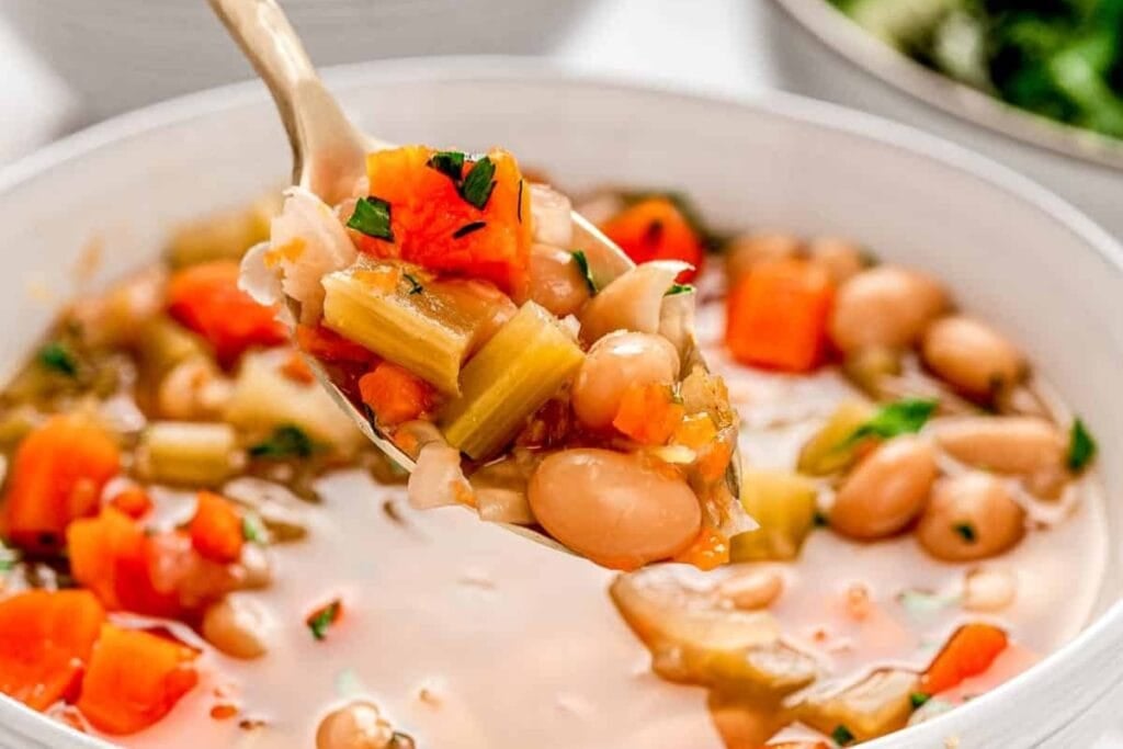 White bean soup scooped with a spoon in a bowl.