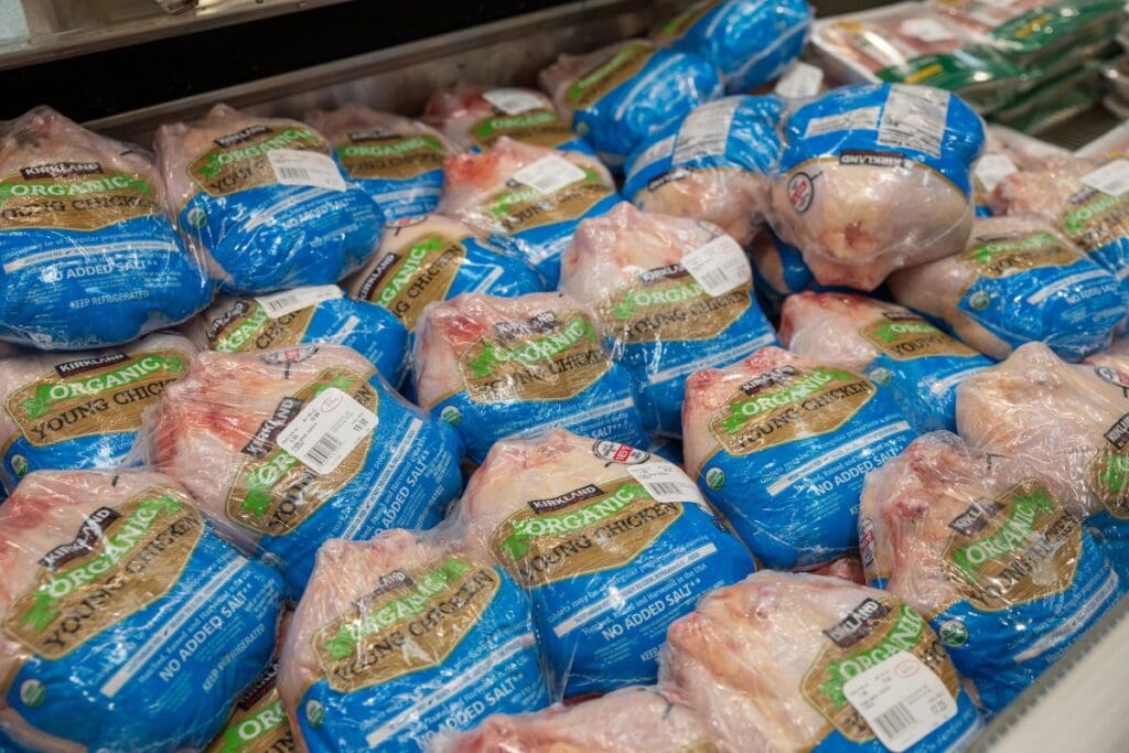 Organic whole chickens in plastic packaging on a grocery store shelf.