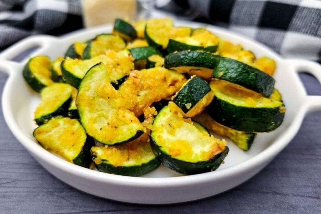 Zucchini with Parmesan in a narrow white handled dish.