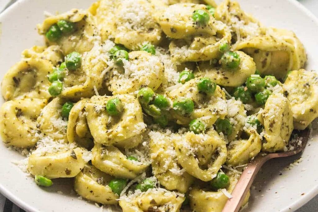 A close up shot of pesto tortillini.