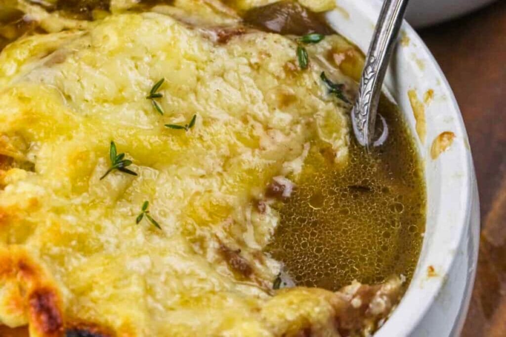 French onion soup with melted cheese and thyme, with a spoon in the bowl.